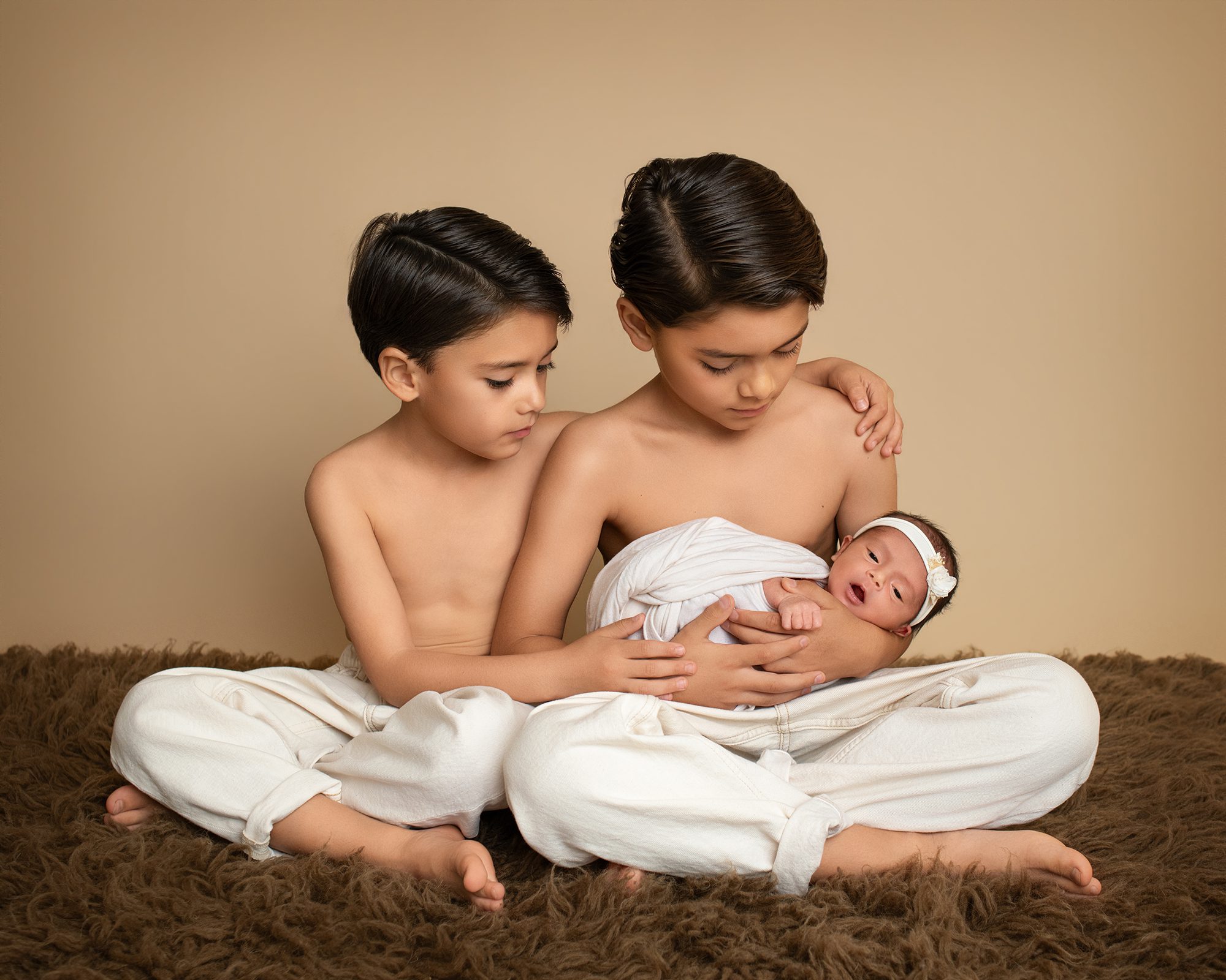 Newborn baby girl wrapped in cream fabric during studio newborn photography session in San Marcos